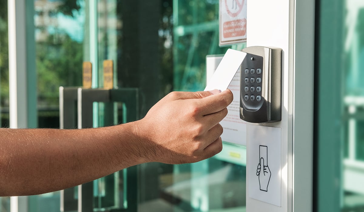 Arm holding out keycard in front of access control reader on sunny day Arm holding out keycard in front of access control reader on sunny day