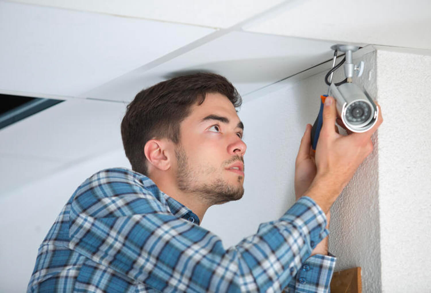 Man installing security camera on ceiling Man installing security camera on ceiling