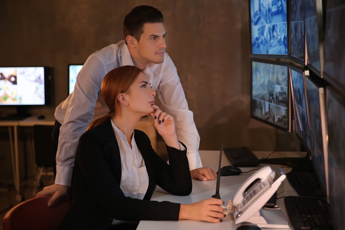 Woman showing man video feed on security monitors Woman showing man video feed on security monitors